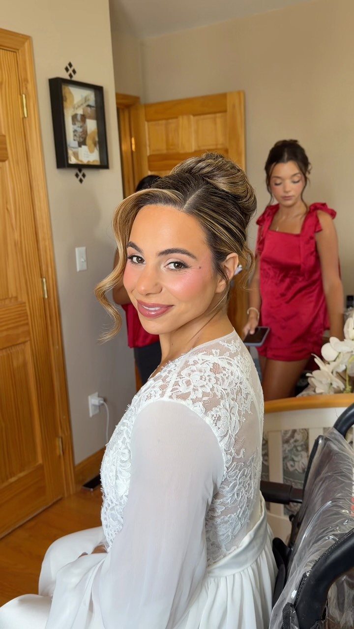 Woman with professional bridal hair and makeup wearing a white lace robe.