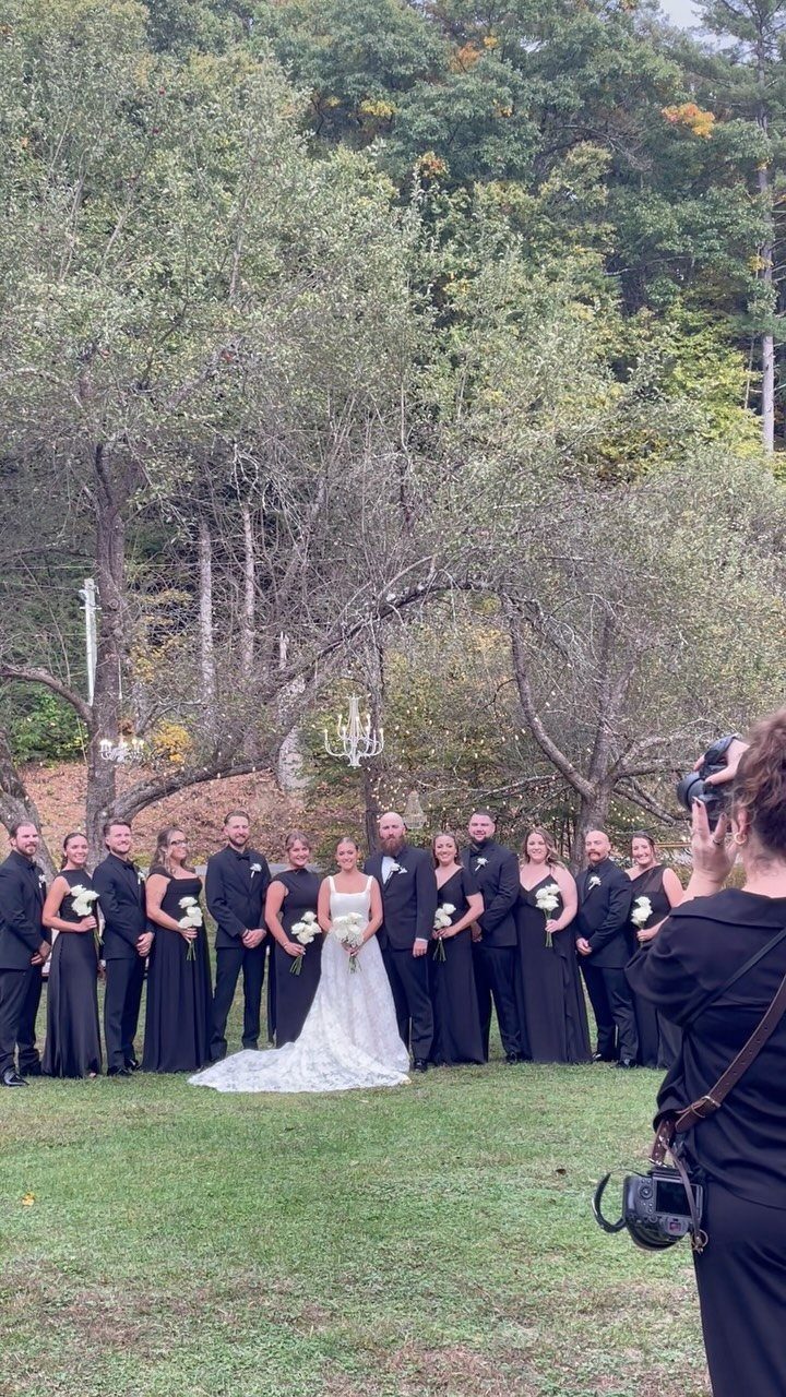 Wedding party posing on a grassy lawn with a forest background.