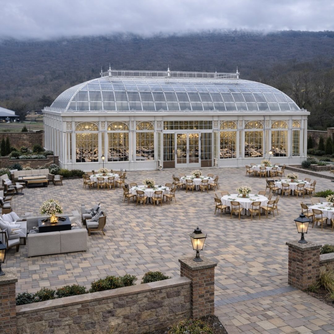 White glass conservatory and stone patio with wedding reception tables overlooking misty mountains