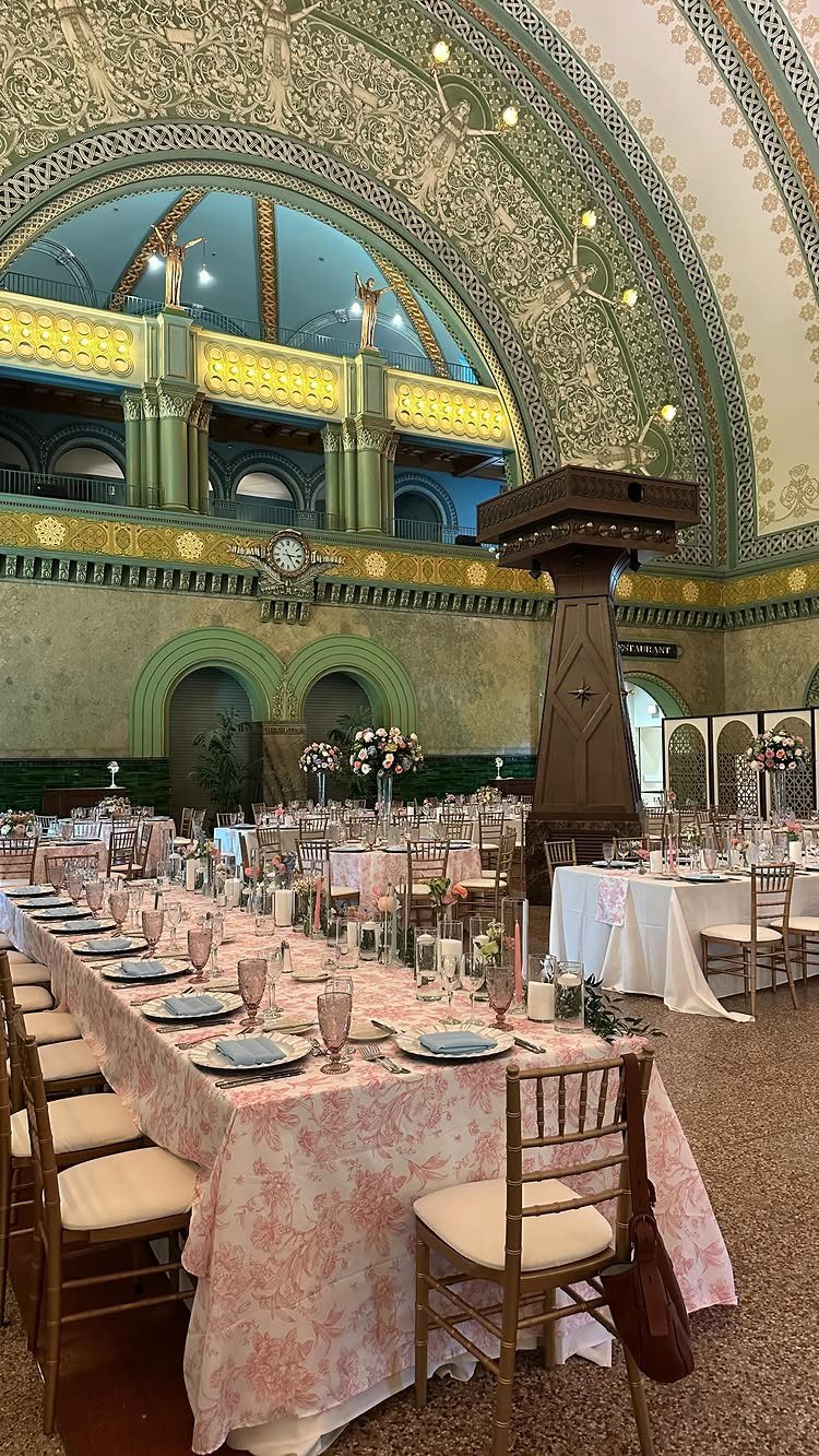 Ornate historic hall with arched ceilings and floral banquet tables set for a wedding.