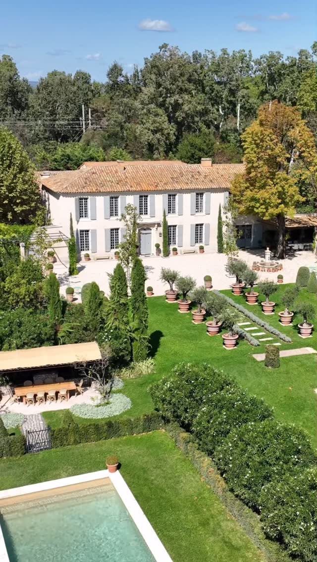 Large white estate with terracotta roof, swimming pool, and manicured gardens.