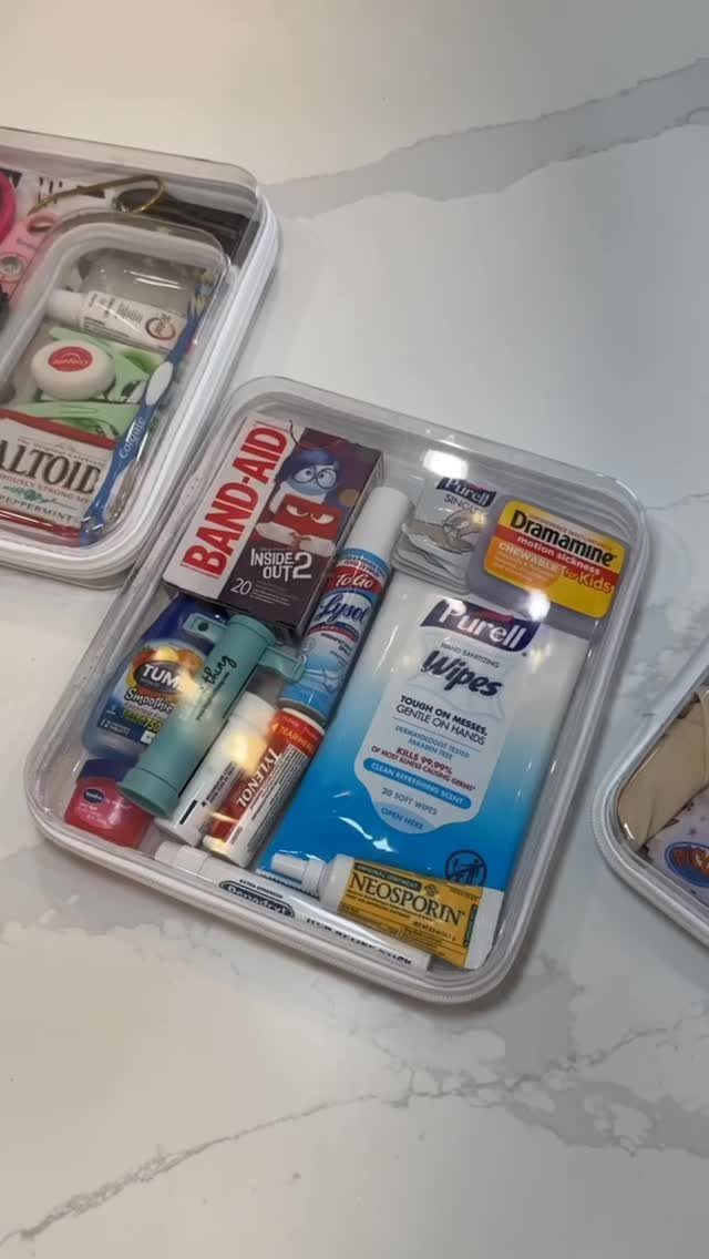 First aid and hygiene supplies organized in clear plastic containers on marble surface.