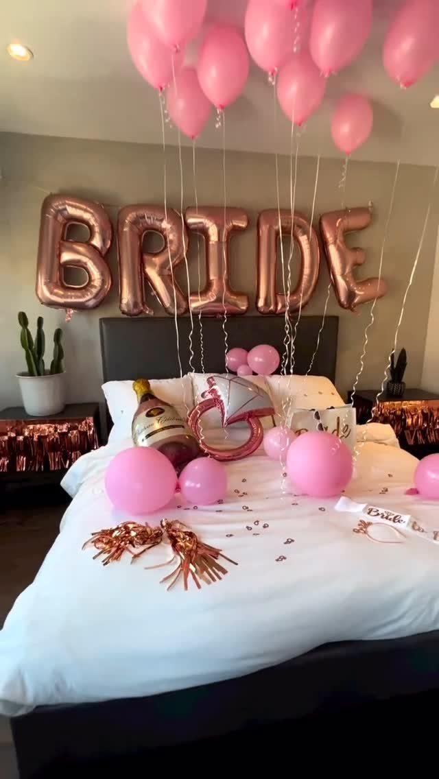Bedroom decorated with pink balloons and rose gold BRIDE balloons for a celebration.