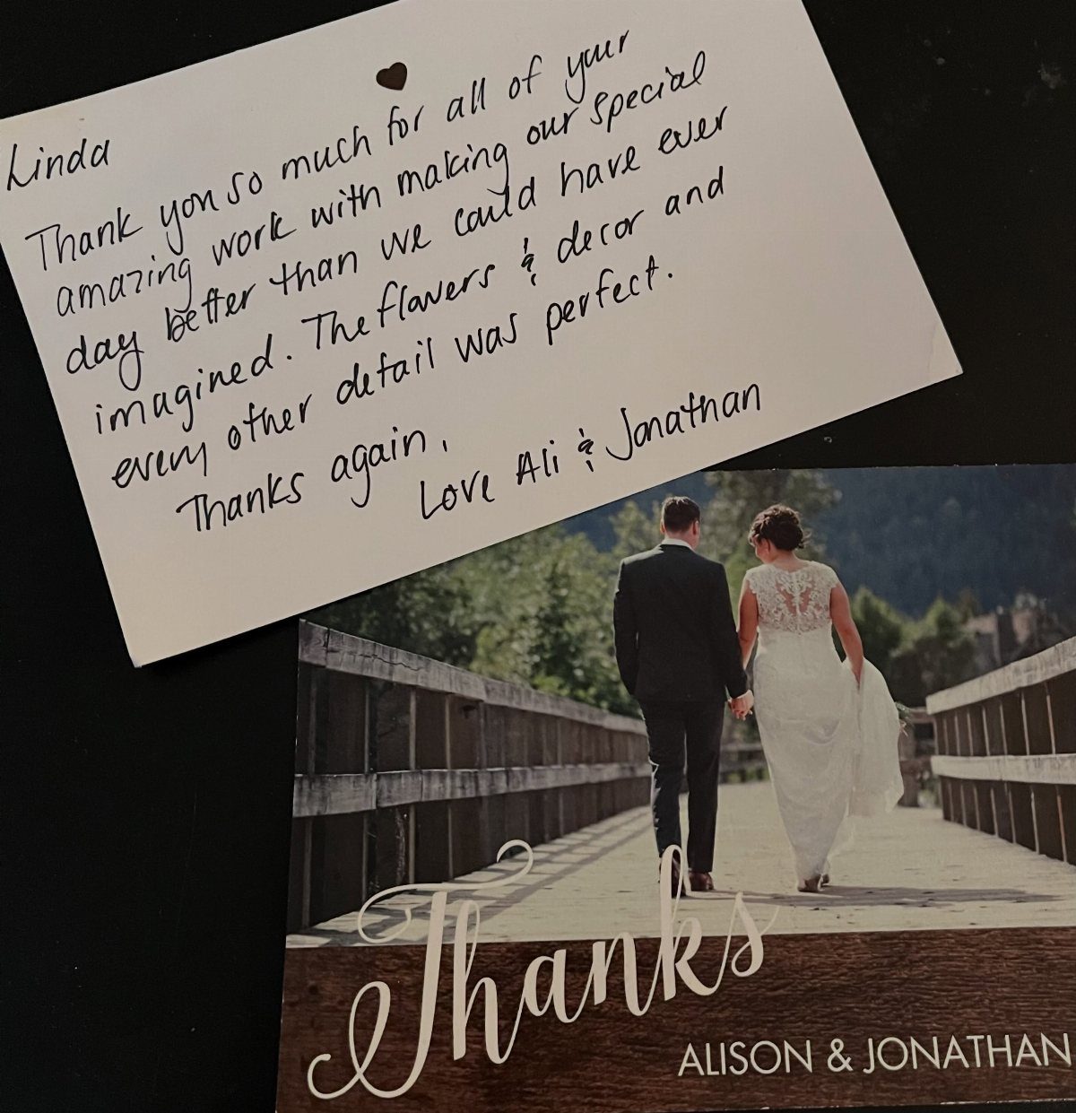 Handwritten thank-you note and a printed card with a wedding couple on a bridge.