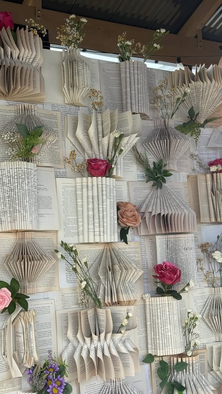 Folded book pages on a wall holding pink and white fresh flowers