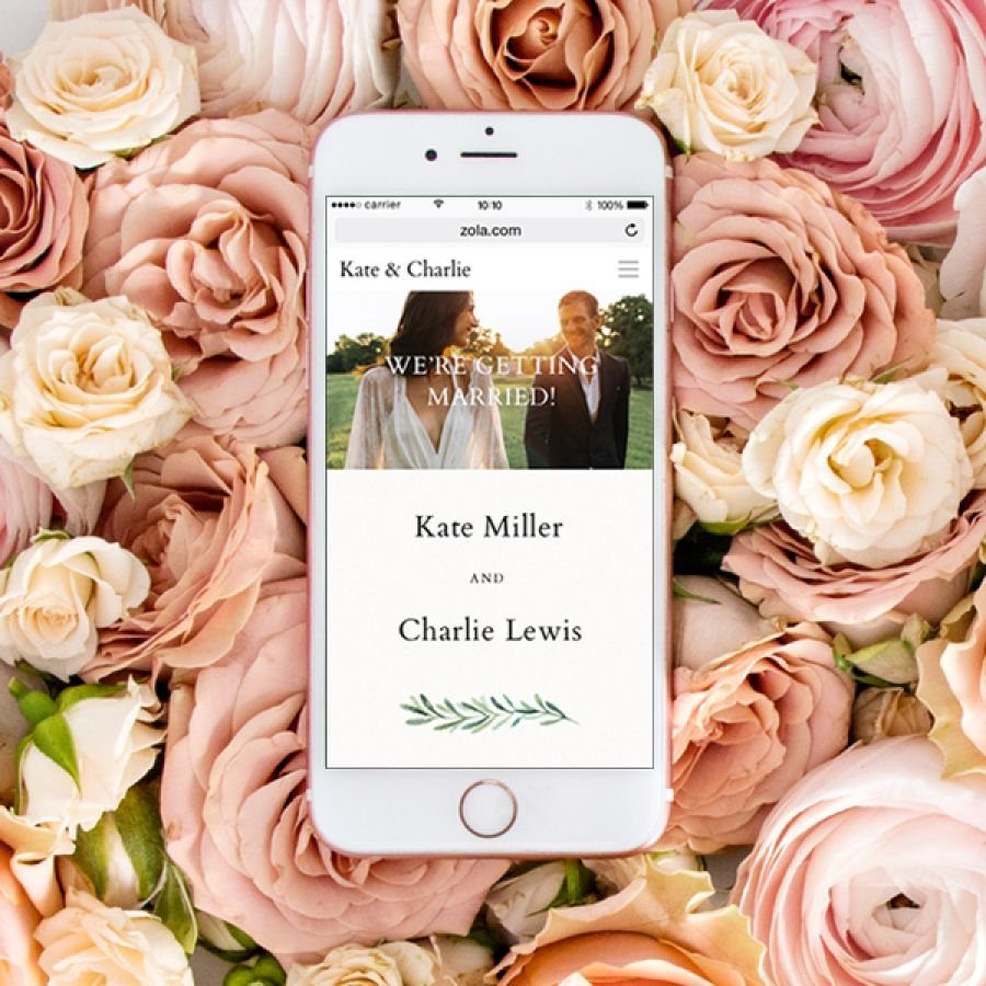 Smartphone displaying a Zola wedding website surrounded by pink and cream roses.