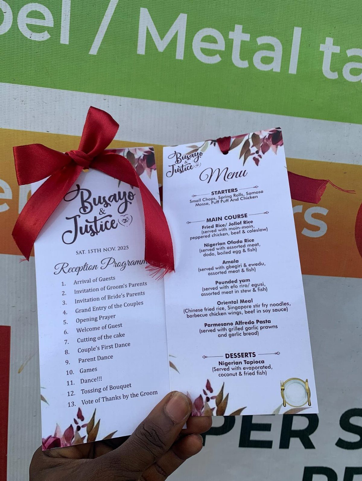 Wedding reception program and menu cards held by a hand with red ribbon.