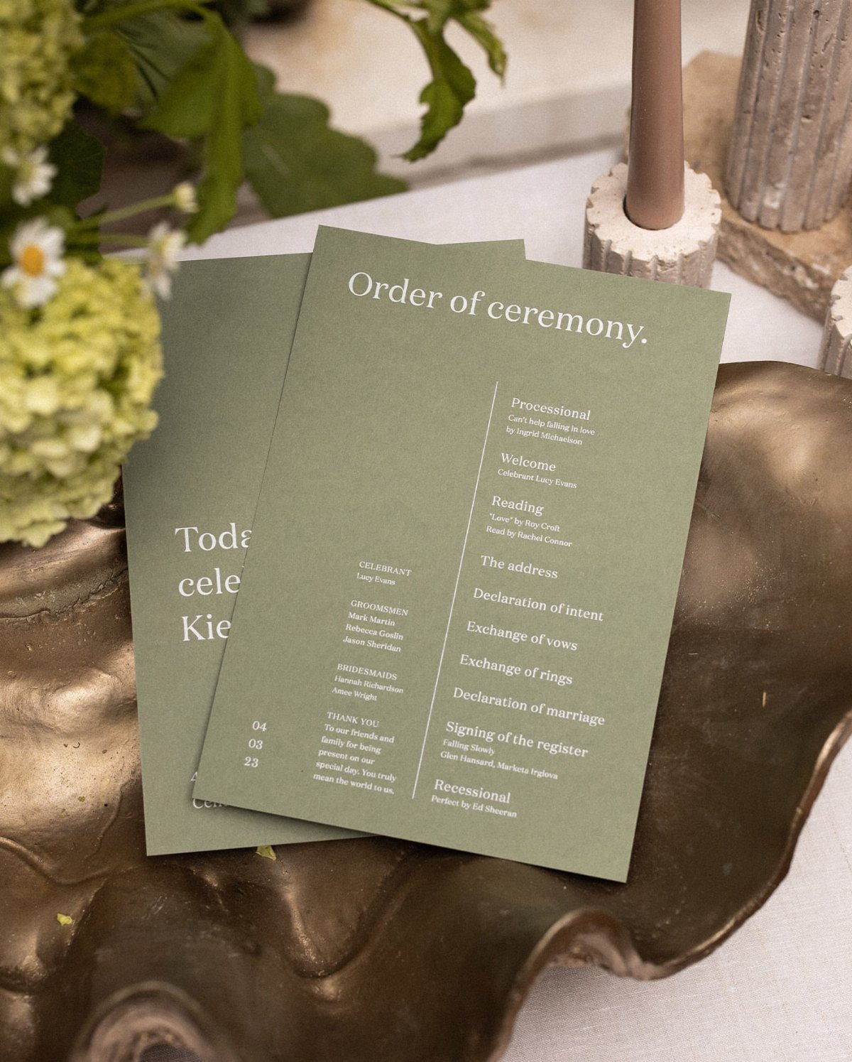 Sage green wedding ceremony programs resting on a gold decorative metallic tray.