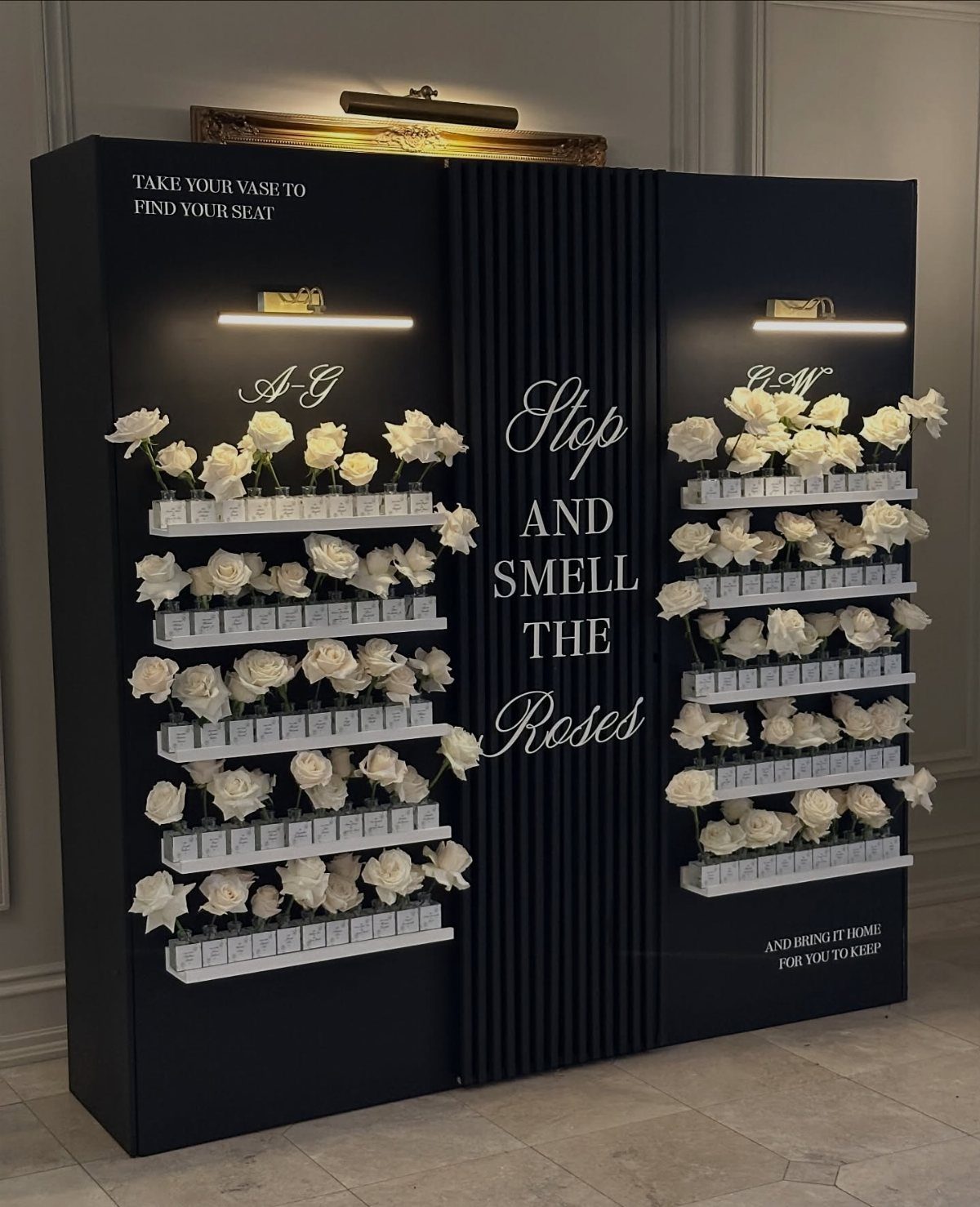 Black wedding seating chart display with white roses and guest name cards.
