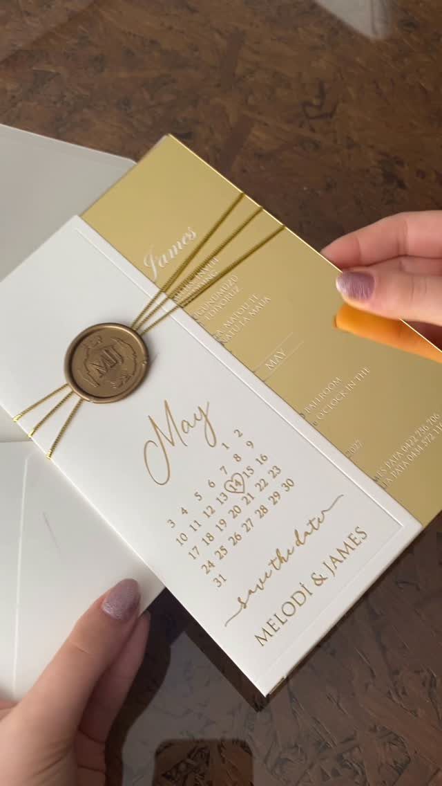 Save-the-date card with gold accents, a wax seal, and a May calendar.