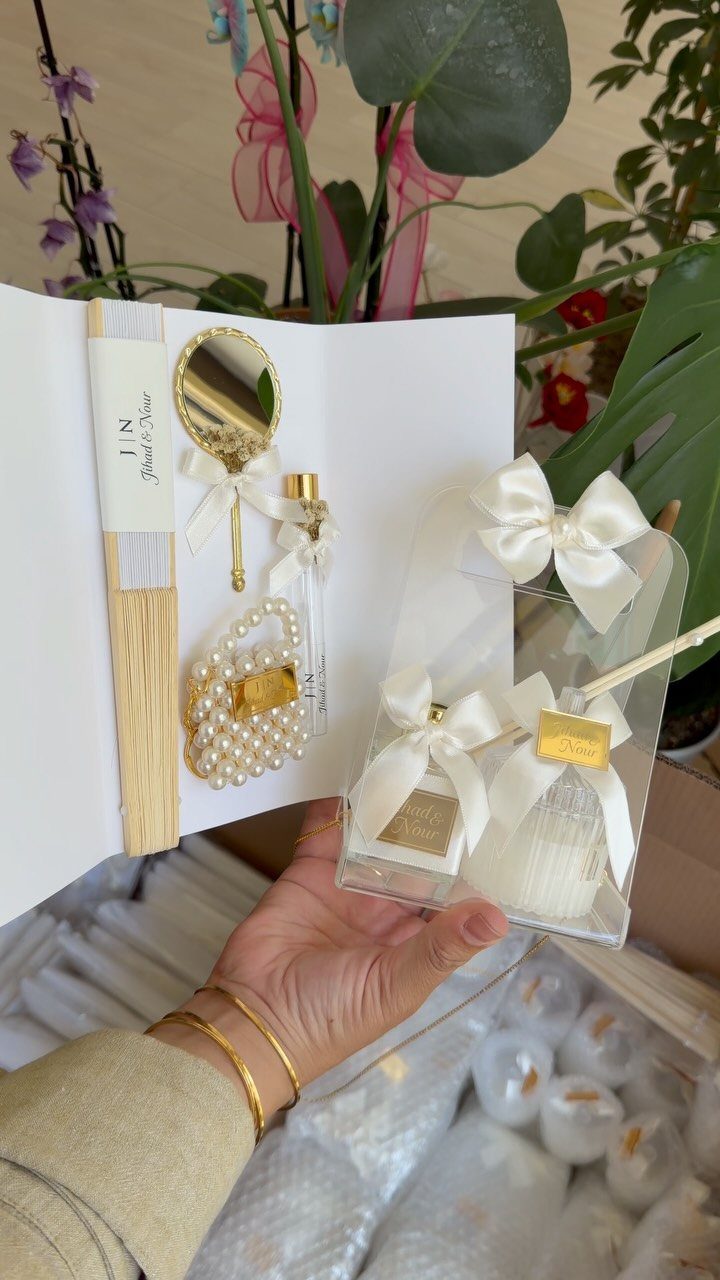White wedding favor gift set with a gold mirror, pearls, and a candle.