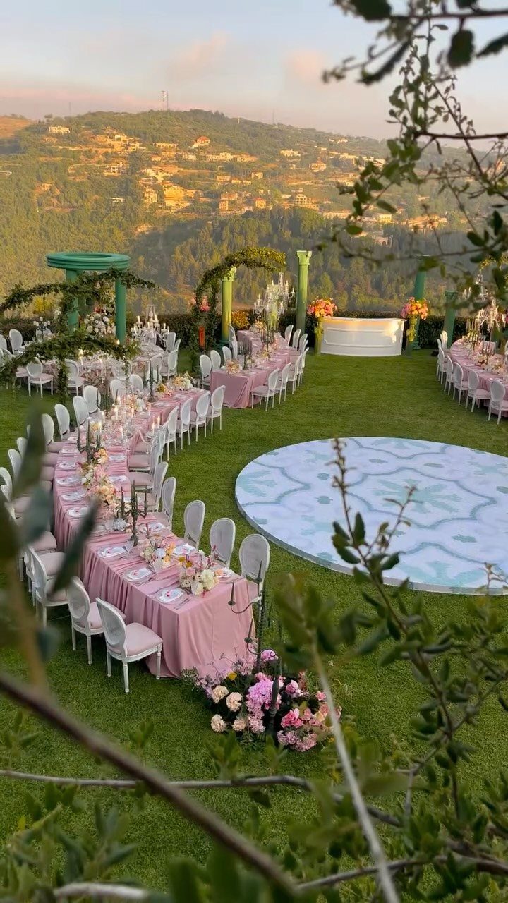 Outdoor wedding reception with pink tables, white chairs, and a circular dance floor.