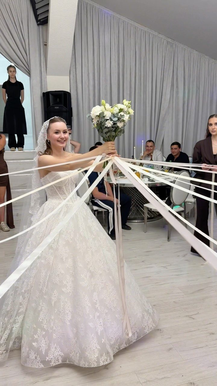 Bride holding a bouquet with ribbons attached for a wedding bouquet toss game