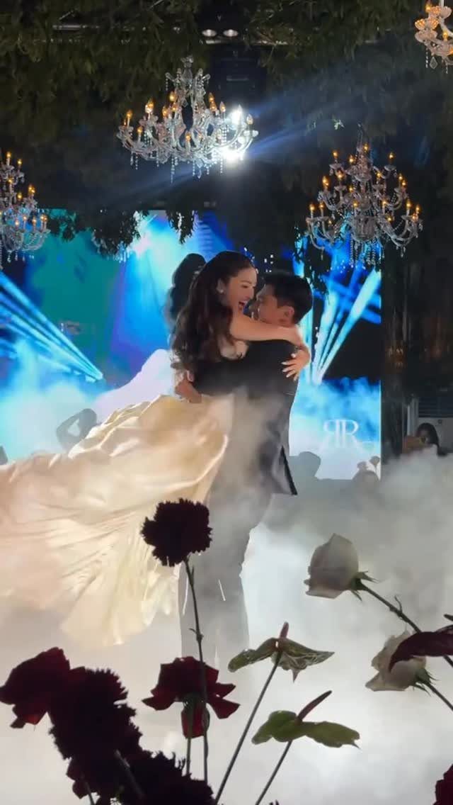 Bride in gold gown and groom dancing in fog under crystal chandeliers