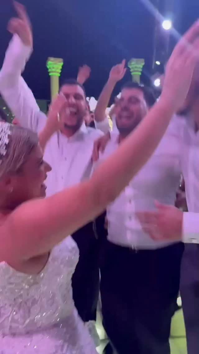 Bride and guests dancing and cheering at an outdoor evening wedding reception party.