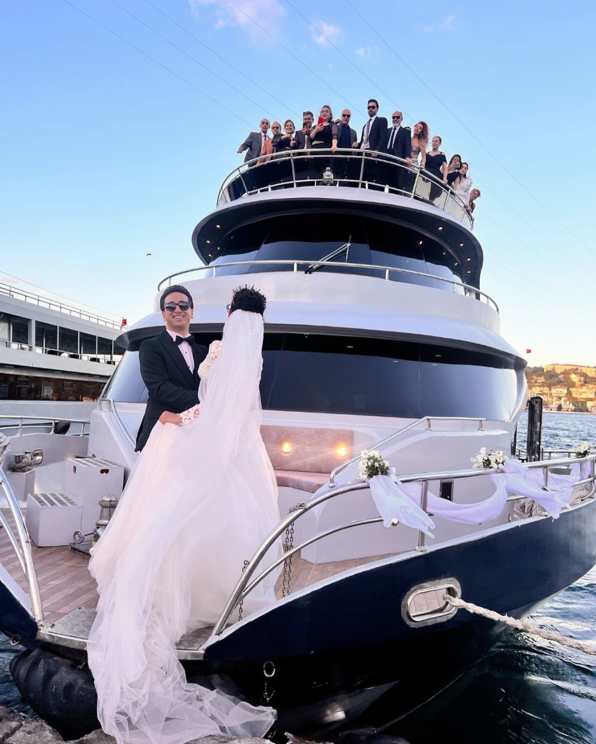 Bride and groom posing on the deck of a luxury wedding event yacht.