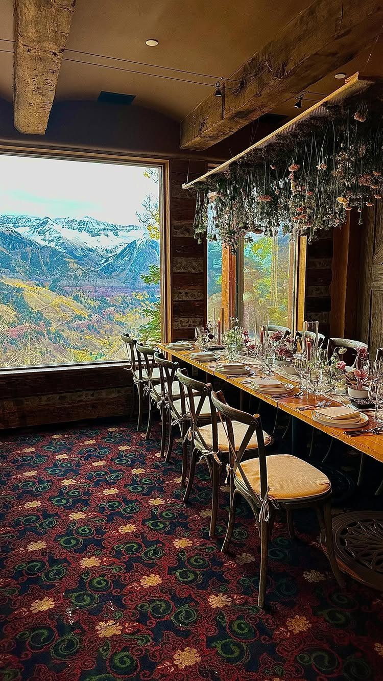 Long wooden dining table set for a meal in a rustic mountain lodge.