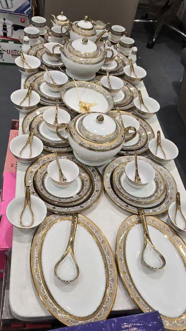 White ceramic dinnerware set with gold ornate patterns arranged on a white table