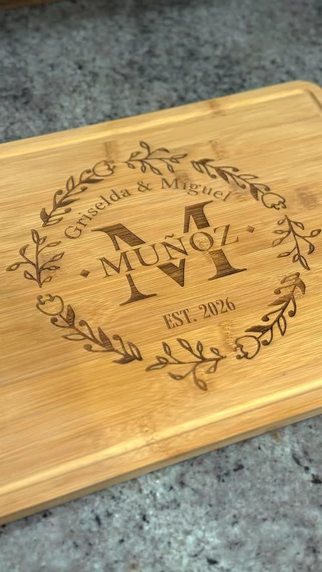 Personalized wooden cutting board engraved with names, surname, and established date.