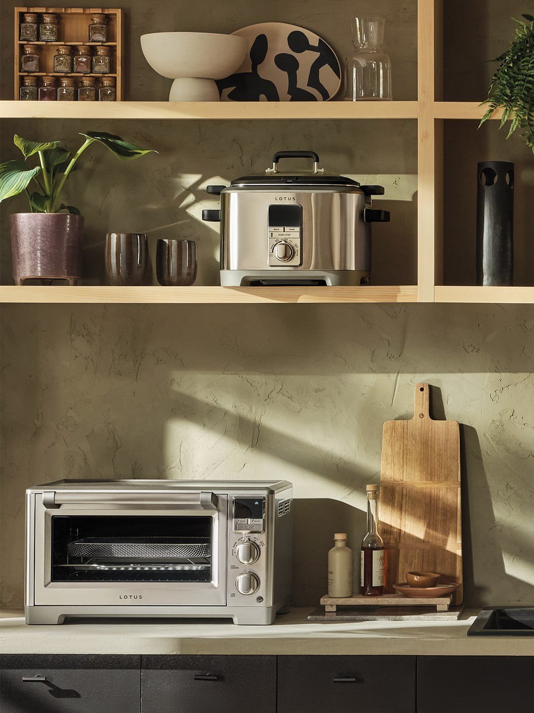 Silver toaster oven on a white kitchen counter with wooden shelves above.