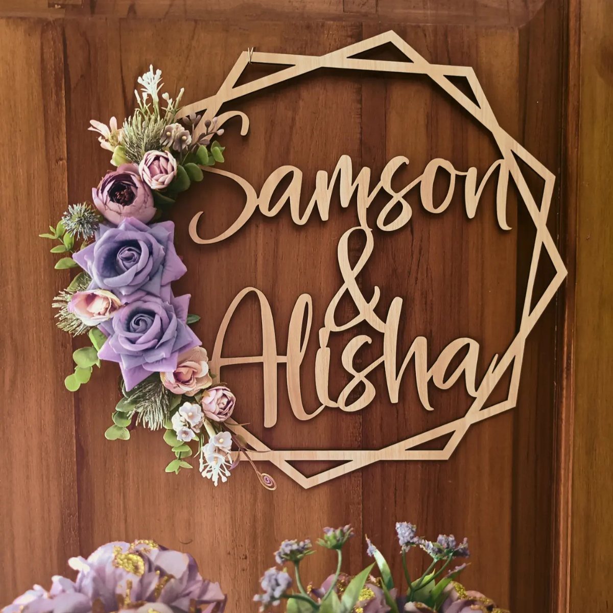 Wooden hexagonal wedding sign with names Samson and Alisha and purple floral accents.