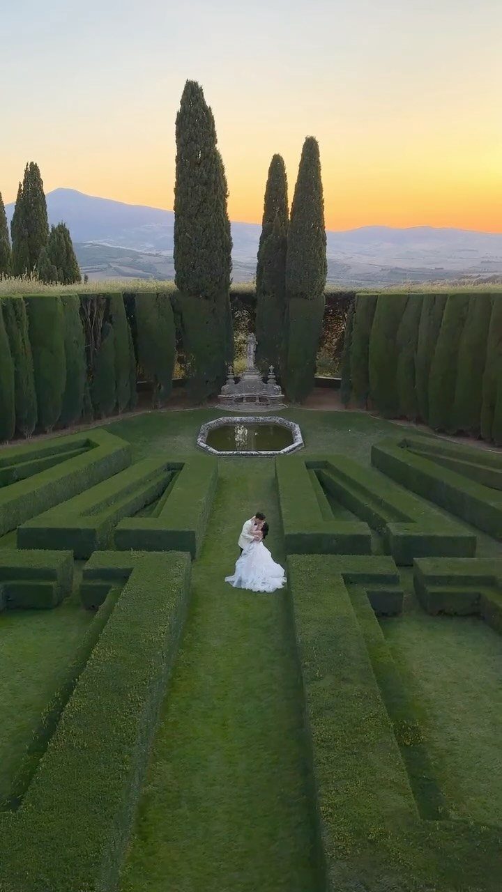 Bride and groom embracing in a geometric hedge garden with Tuscan hills background