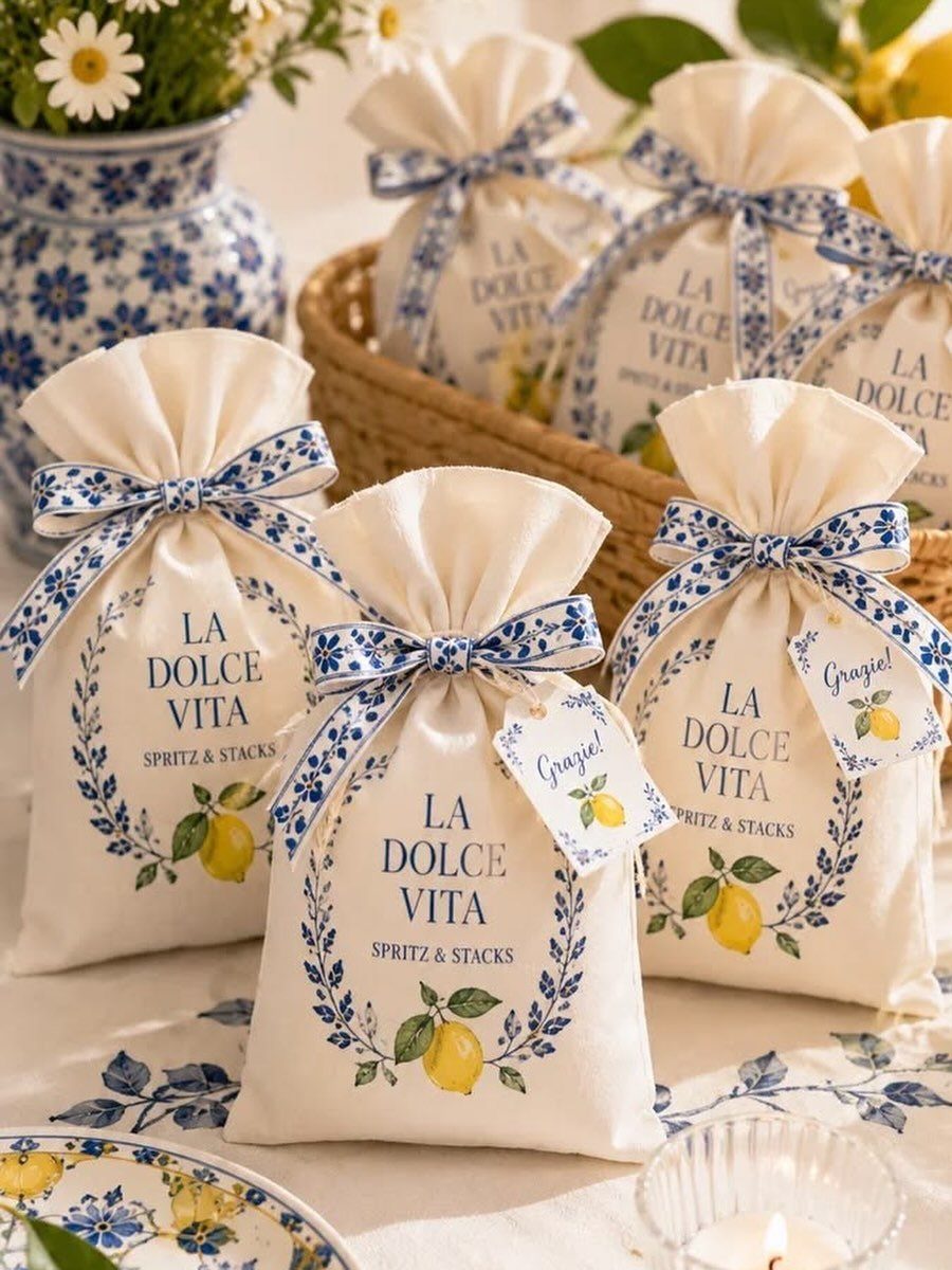 White fabric wedding favor pouches with lemon illustrations and blue patterned ribbons.