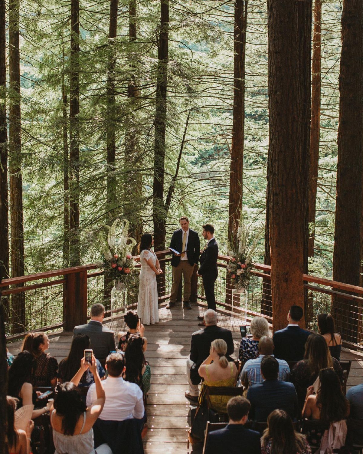 Wedding ceremony on a wooden deck surrounded by tall redwood forest trees.