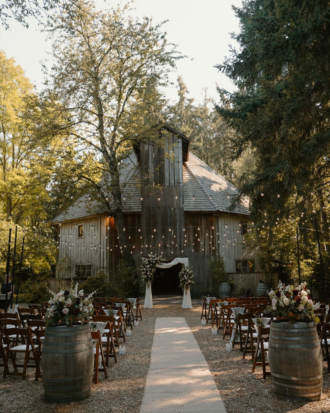 Rustic wooden barn wedding venue in a forest with an aisle and floral arch