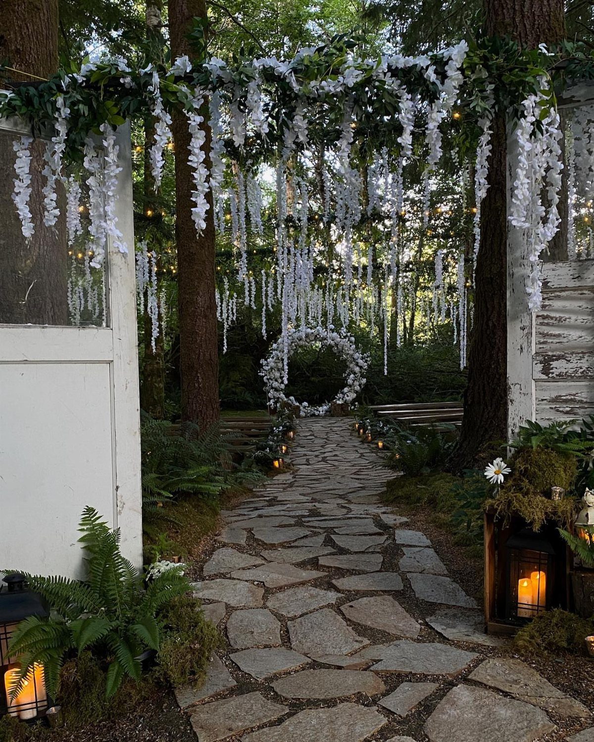 Stone path leading to a circular floral arch in a lush forest setting