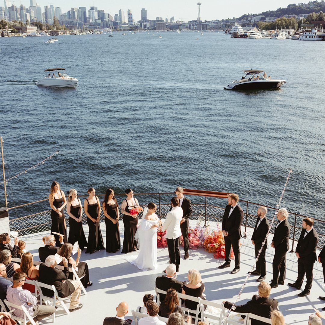 Wedding ceremony on a boat deck with a city skyline across the lake.