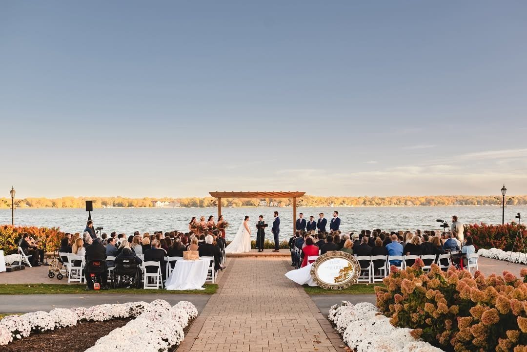 Wedding ceremony with a wooden altar and guests overlooking a calm blue lake.