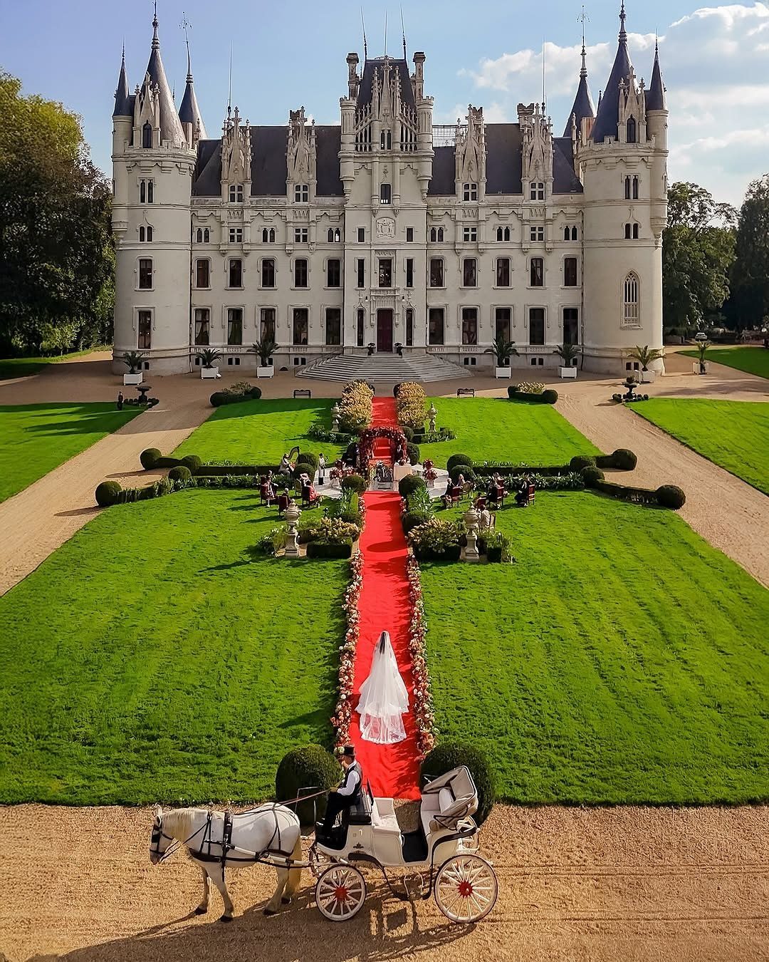 White castle with a red carpet and horse-drawn carriage for an outdoor wedding