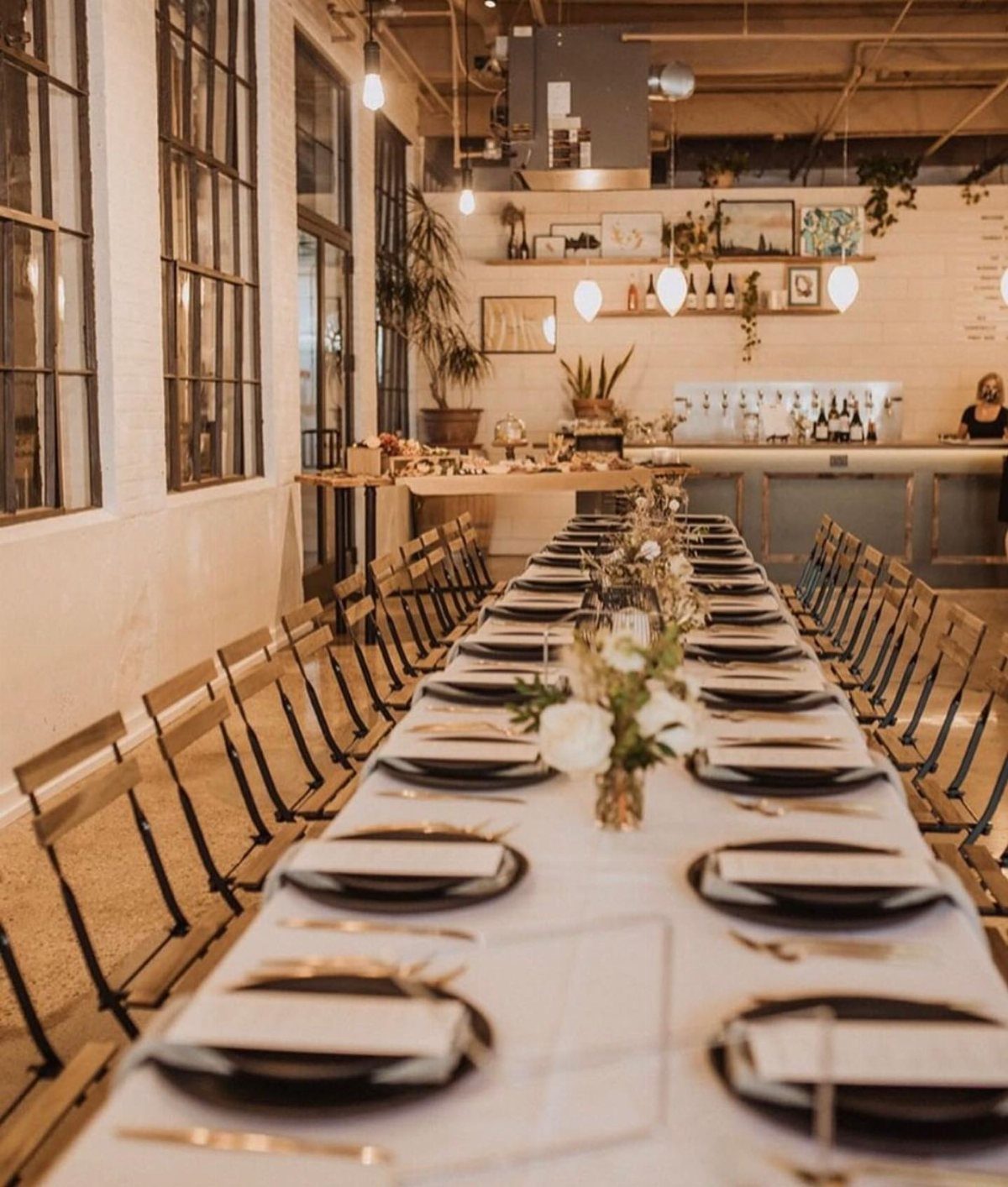 Long wedding table with black plates in an industrial brewery venue with beer taps.