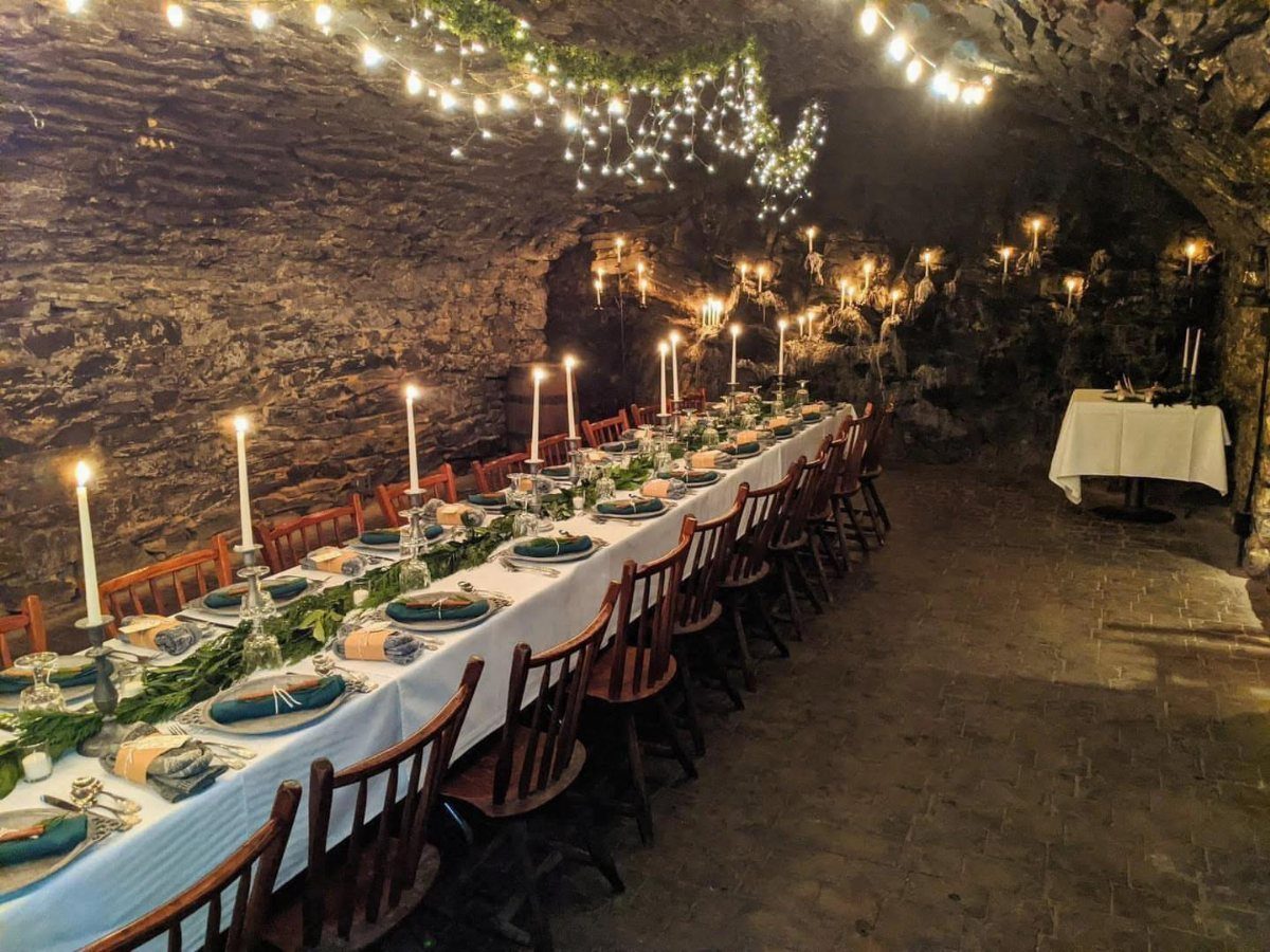 Long wedding table with candles and blue linens in a stone cellar venue