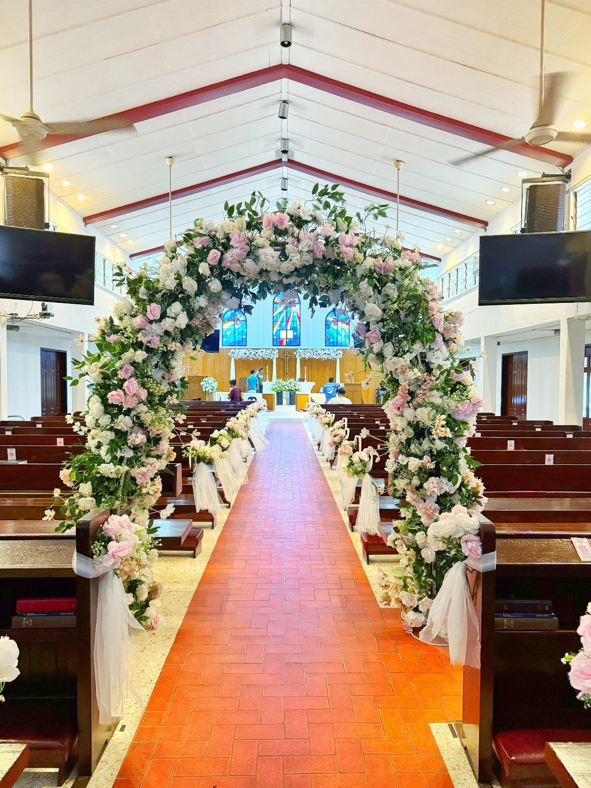 Church interior with a floral arch and red brick aisle for a wedding ceremony