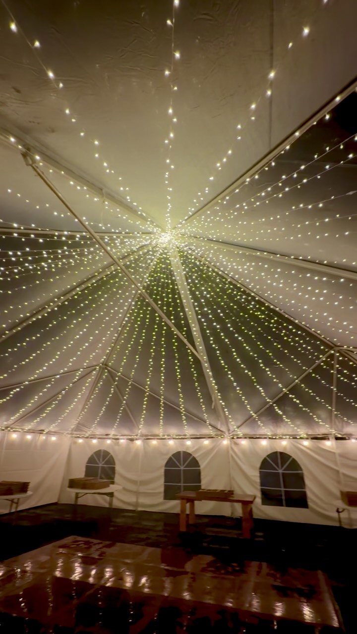 String lights radiating from the center of a white event tent ceiling.