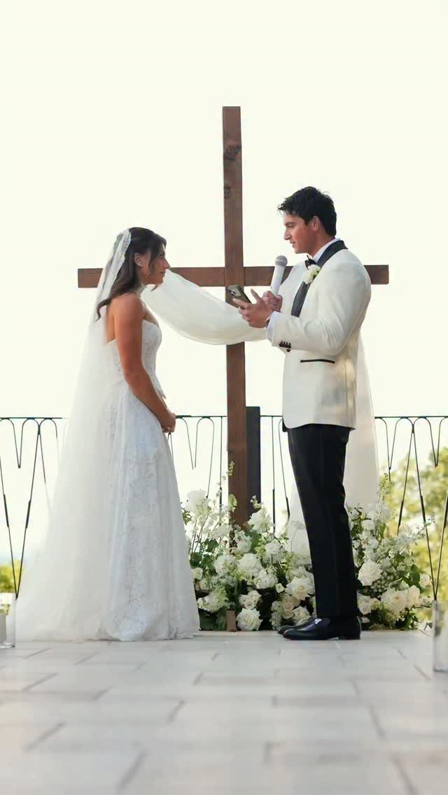 Bride and groom standing before a wooden cross during a wedding ceremony.